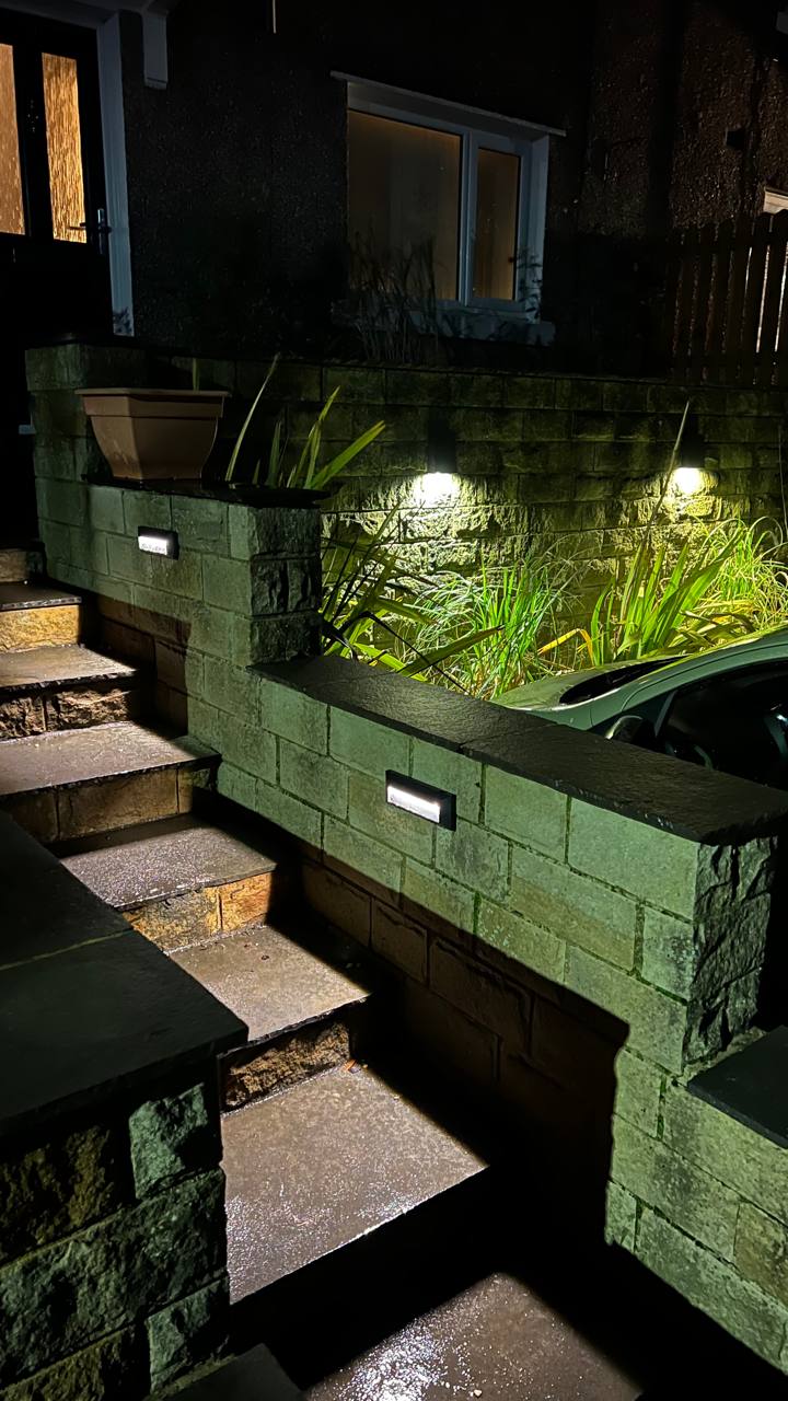 Exterior step and wall lighting illuminating a property entrance at night