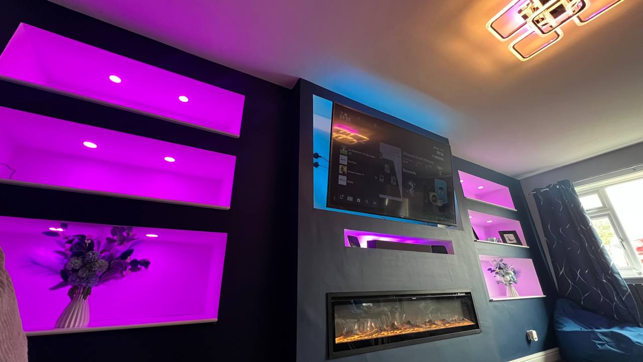 Bespoke media wall with LED-lit alcoves and integrated fireplace viewed from the side